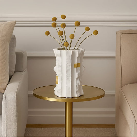 Astra white ceramic vase with gold accent details styled on a round brass table between two beige sofas adding a modern luxury touch to living room decor.