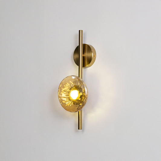 Modern wall light in gold metal finish with glass globe shade for bedroom or living room decor lighting white background.