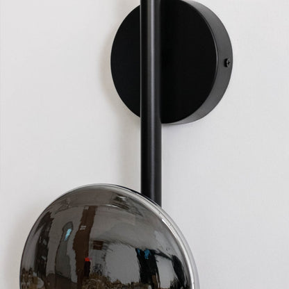 Closeup of black wall light with smoked textured glass shade highlighting unique texture and modern design.