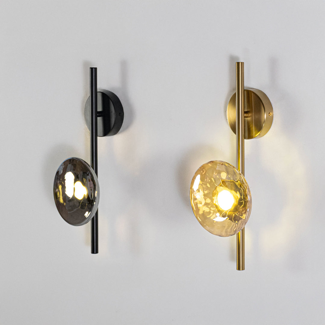 Modern wall light set in black and gold metal finish with glass globe shades for bedroom or living decor lighting white background.
