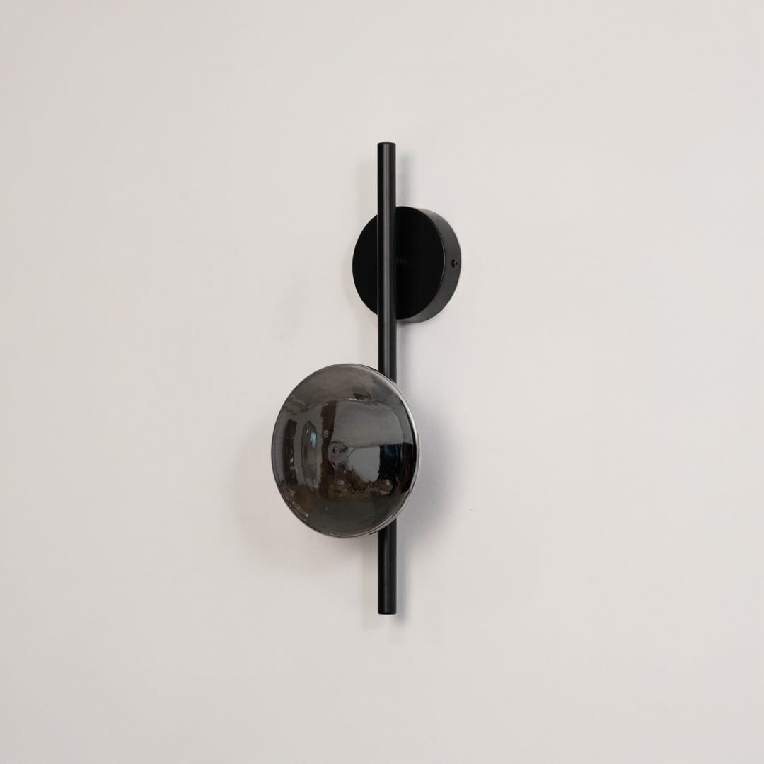 Black wall light with smoked glass shade shown on a plain white background with lights off for clear detailing.