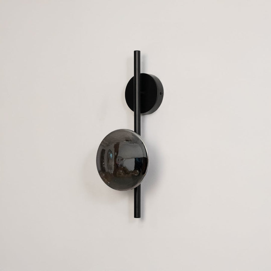Black wall light with smoked glass shade shown on a plain white background with lights off for clear detailing.