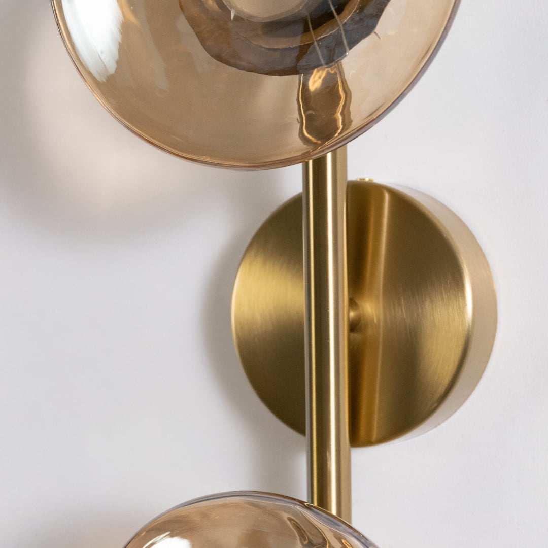 Closeup of gold double wall light with amber textured glass globes highlighting detailed texture and elegant finish.