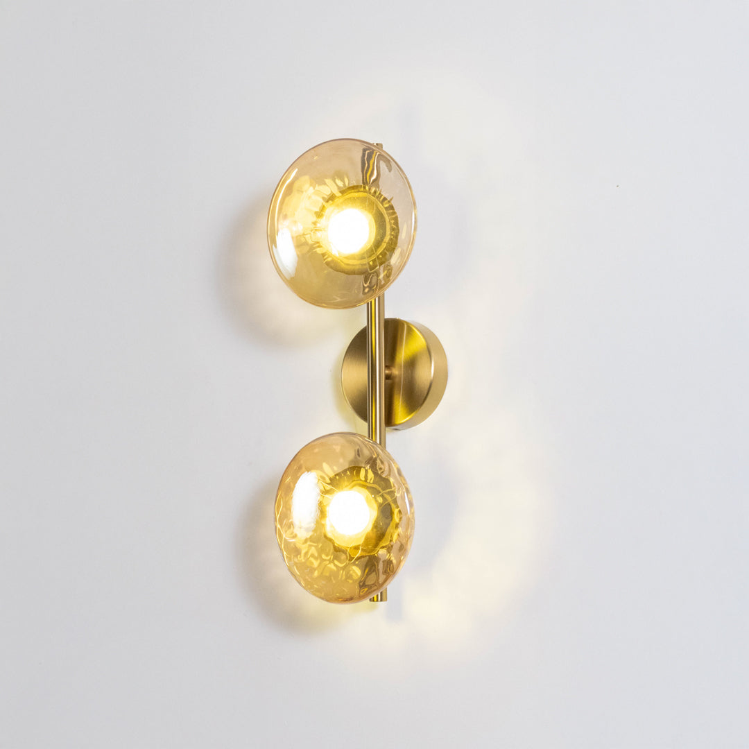 Decorative wall light in gold metal finish with double glass globes for bedroom or living room decor lighting white background.