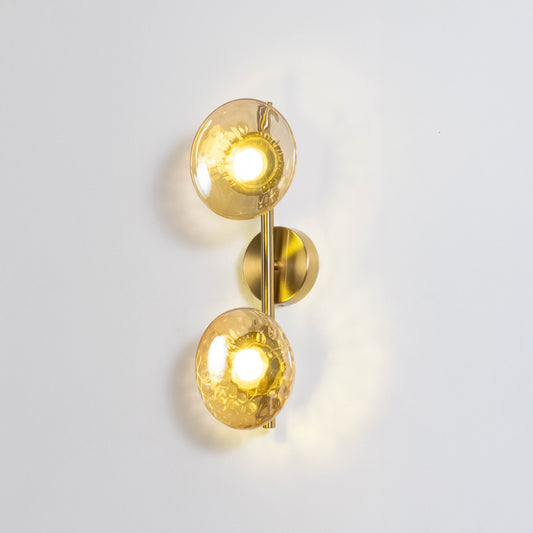 Decorative wall light in gold metal finish with double glass globes for bedroom or living room decor lighting white background.