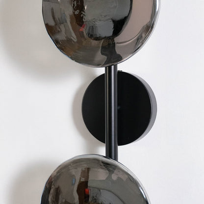 Detailed closeup view of smoked glass globe shade and black metal hardware on modern dual light wall sconce fixture.