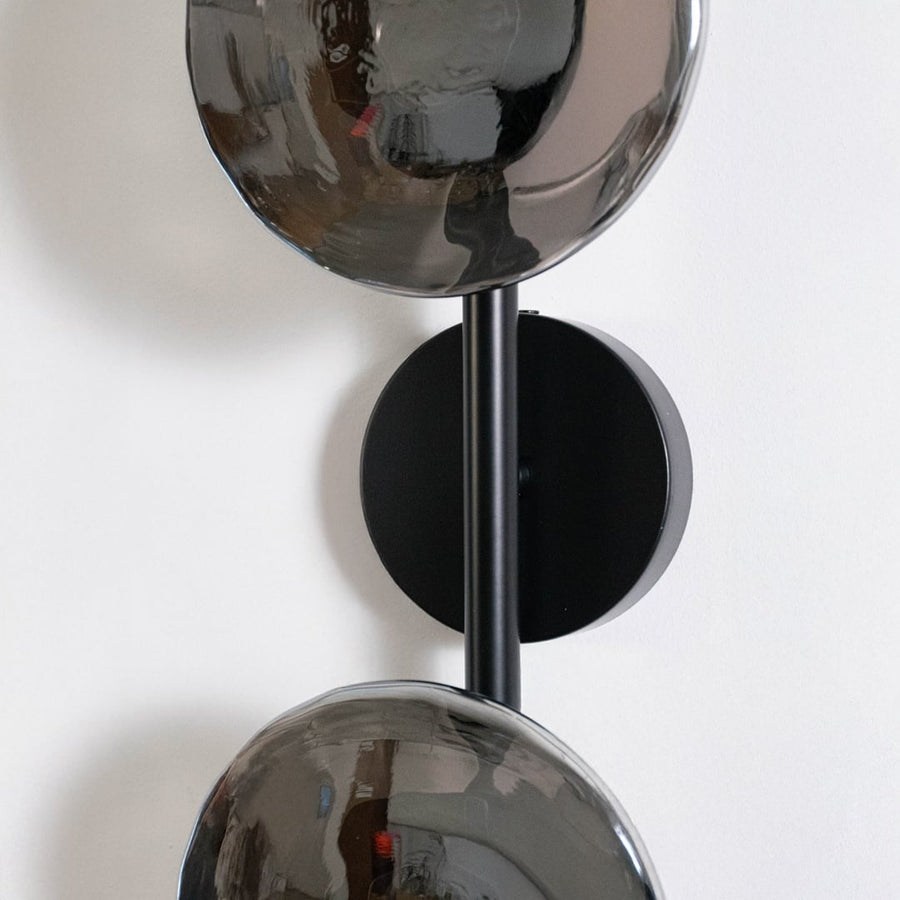 Detailed closeup view of smoked glass globe shade and black metal hardware on modern dual light wall sconce fixture.