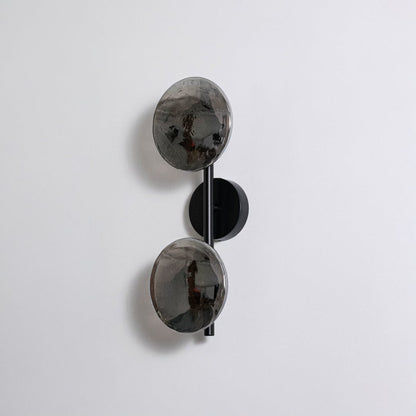 Contemporary black metal dual globe wall light fixture with smoked glass shades turned off on clean white background.