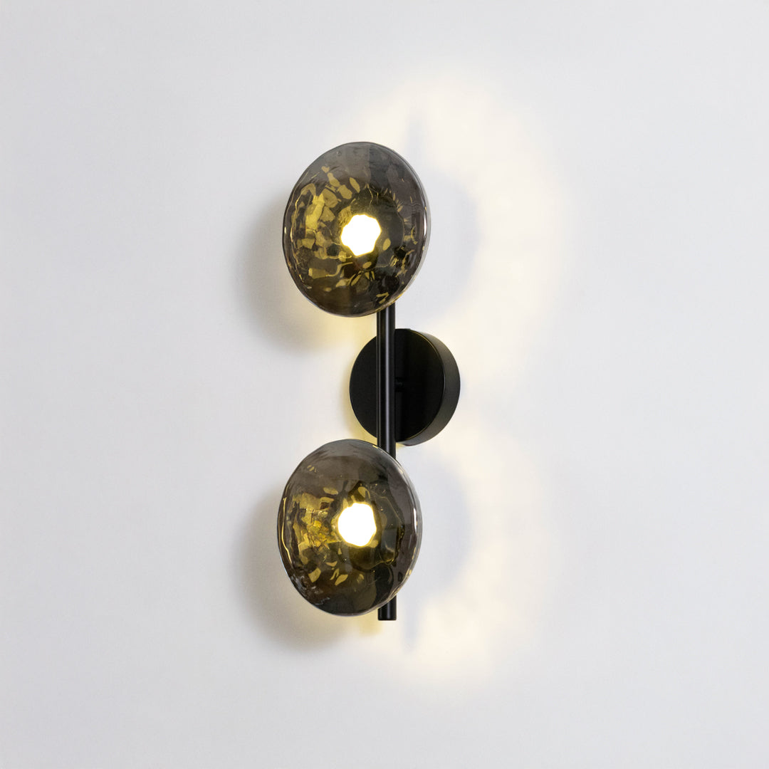 Contemporary wall light in black and gold metal finish with dual globe shades for bedroom or living decor lighting white background.