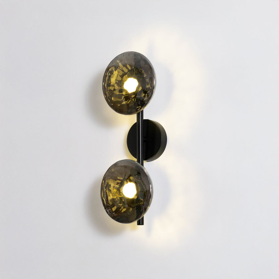 Contemporary wall light in black and gold metal finish with dual globe shades for bedroom or living decor lighting white background.