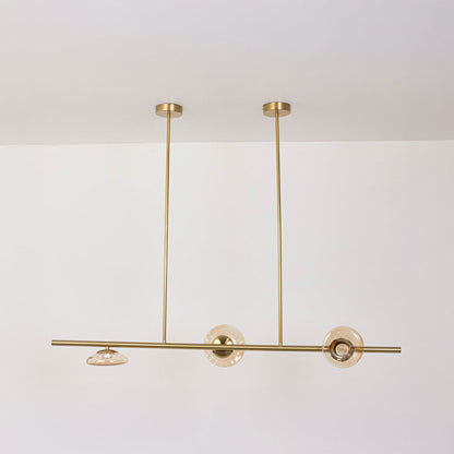 Golden metal linear chandelier with amber glass discs displayed off on white background for sophisticated modern home design.