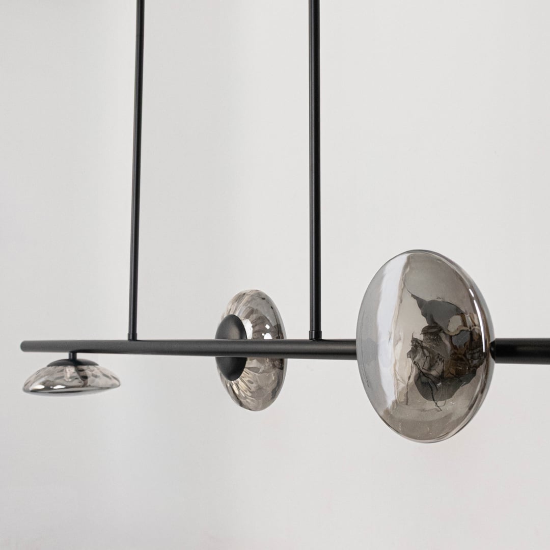 Closeup of black metal chandelier showing smoky glass shades and sleek rod detailing for modern ceiling light design.
