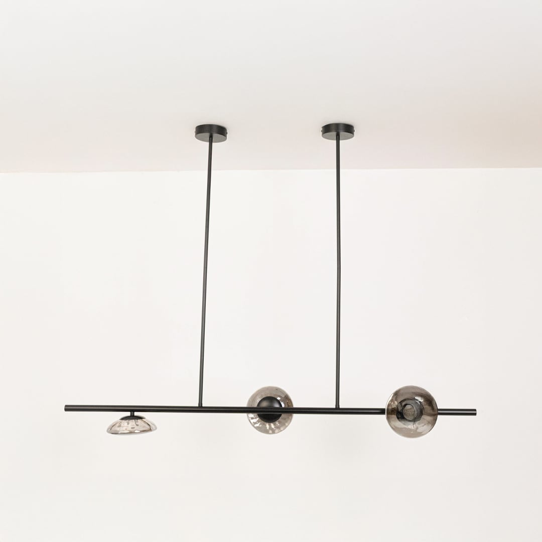 Black metal linear chandelier with smoky glass discs displayed off on white background highlighting elegant home decor piece.