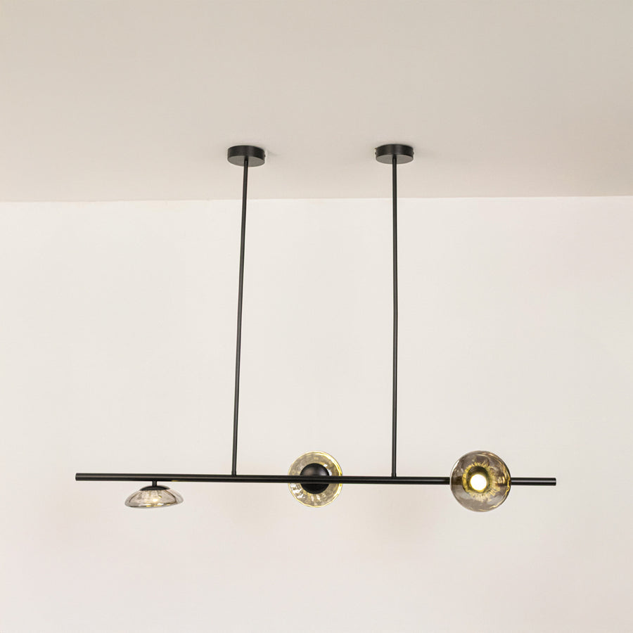 Black metal linear chandelier with circular glass accents designed for sleek modern ceiling lighting in contemporary interiors.