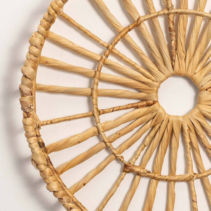 Detailed closeup of handcrafted natural rattan open center web wall basket wheel panel for artisan bohemian home decor.