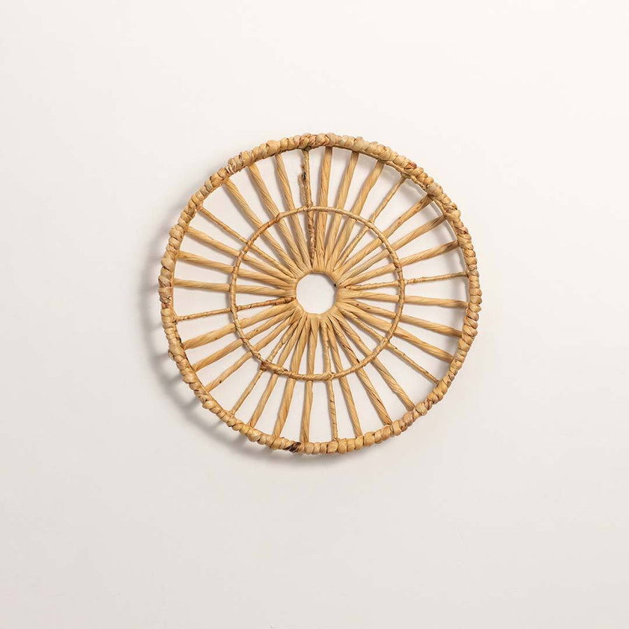 Round handcrafted natural rattan open center web wall basket wheel panel on white background for boho home wall decor display.