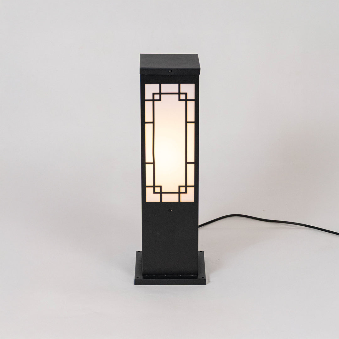 Black outdoor bollard light with geometric frosted panels for modern exterior decor use.