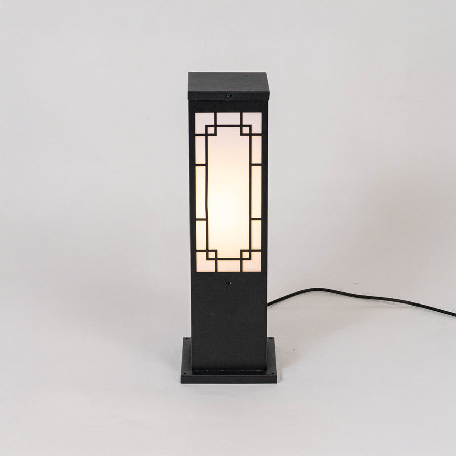Black outdoor bollard light with geometric frosted panels for modern exterior decor use.