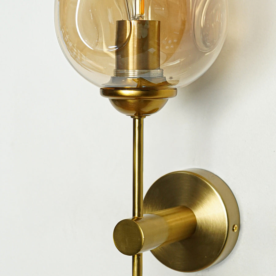 Elegant brass wall light with amber glass shade and sleek metallic finish for luxury interior decor.