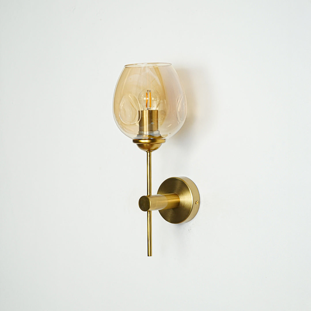 Modern brass wall light with amber glass shade for elegant bedroom and hallway interior decor.