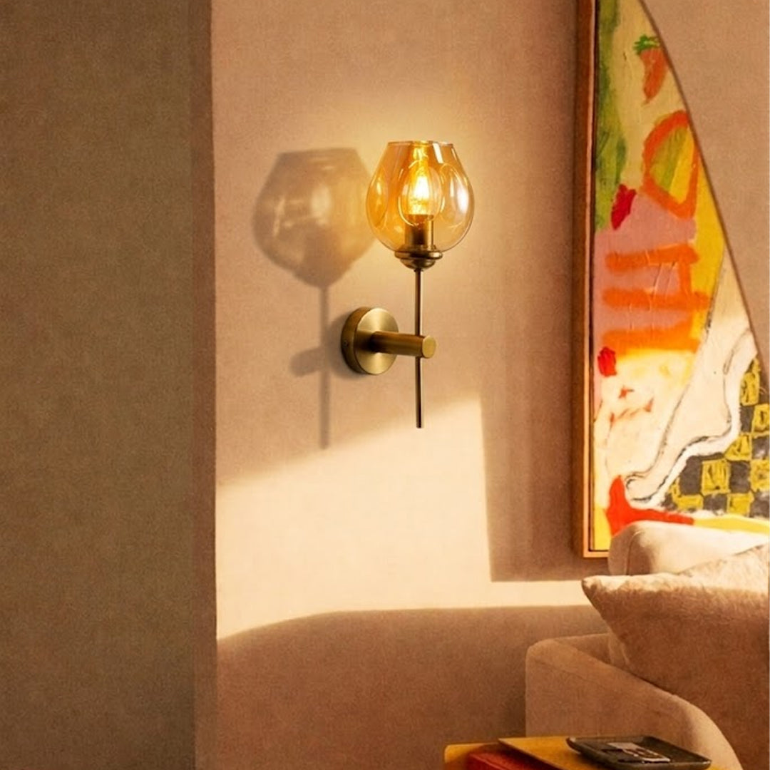 Modern brass wall light with amber glass shade creating warm cozy living room interior ambiance.