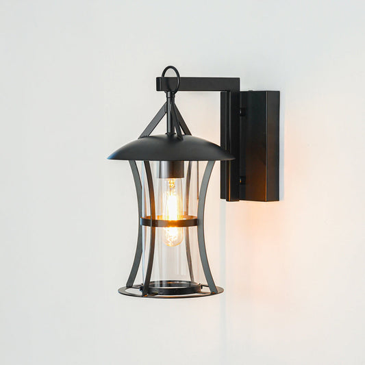 Modern black metal wall light with transparent glass enclosure on clean white wall background perfect for outdoor garden or balcony lighting setup.