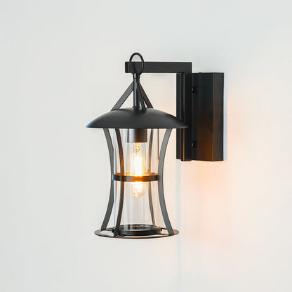 Modern black metal wall light with transparent glass enclosure on clean white wall background perfect for outdoor garden or balcony lighting setup.