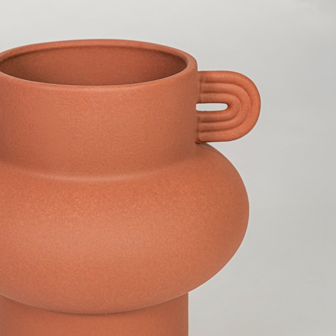 Orange ceramic flower vase closeup with matte finish modern decorative vase for shelf console living room decor styling.