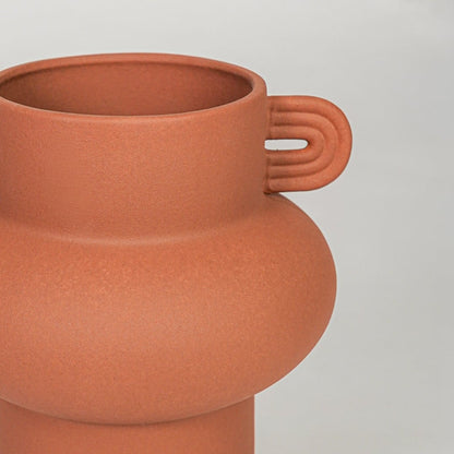 Orange ceramic flower vase closeup with matte finish modern decorative vase for shelf console living room decor styling.
