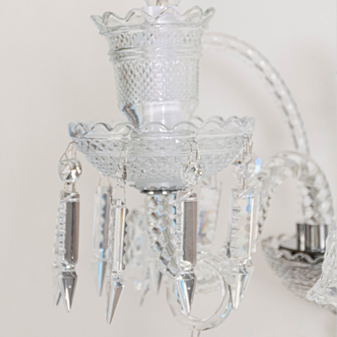 Closeup of crystal wall light with detailed glass shade and crystal accents for elegant wall decor.