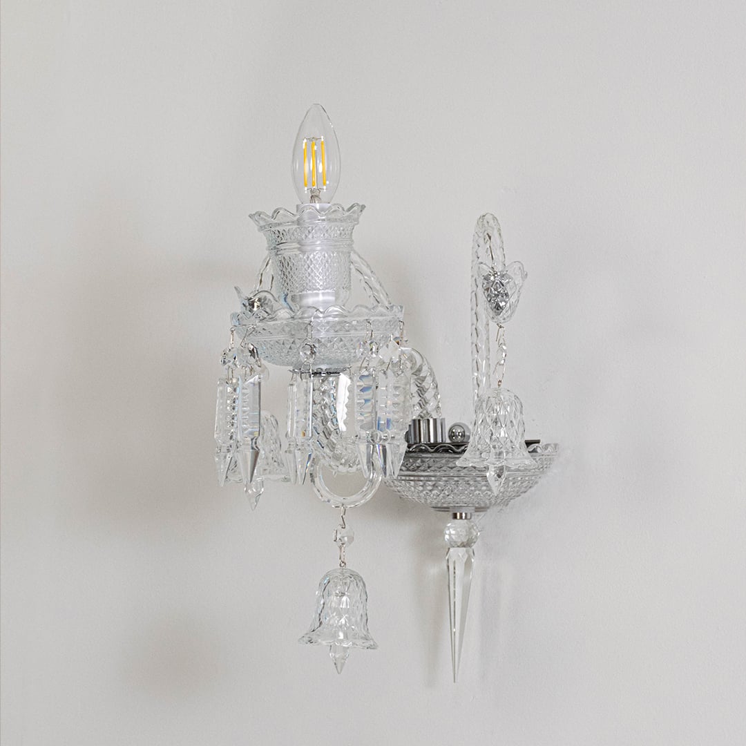 Crystal wall light with ornate glass shade and crystal detailing turned off on white background decor.
