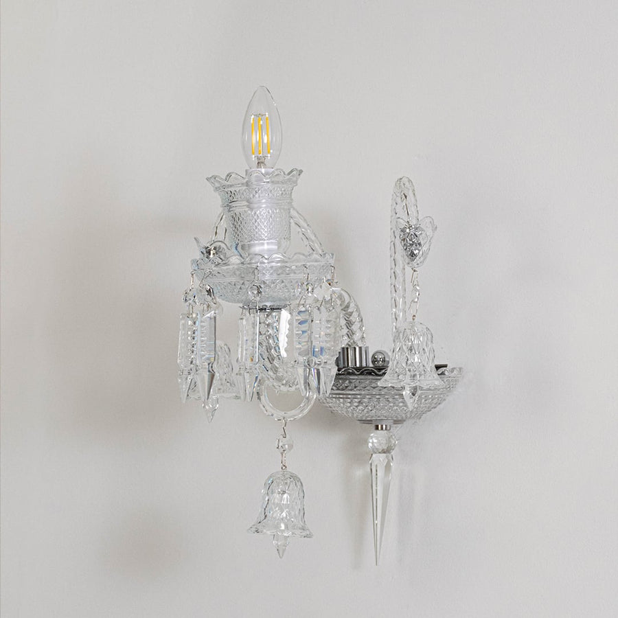 Crystal wall light with ornate glass shade and crystal detailing turned off on white background decor.