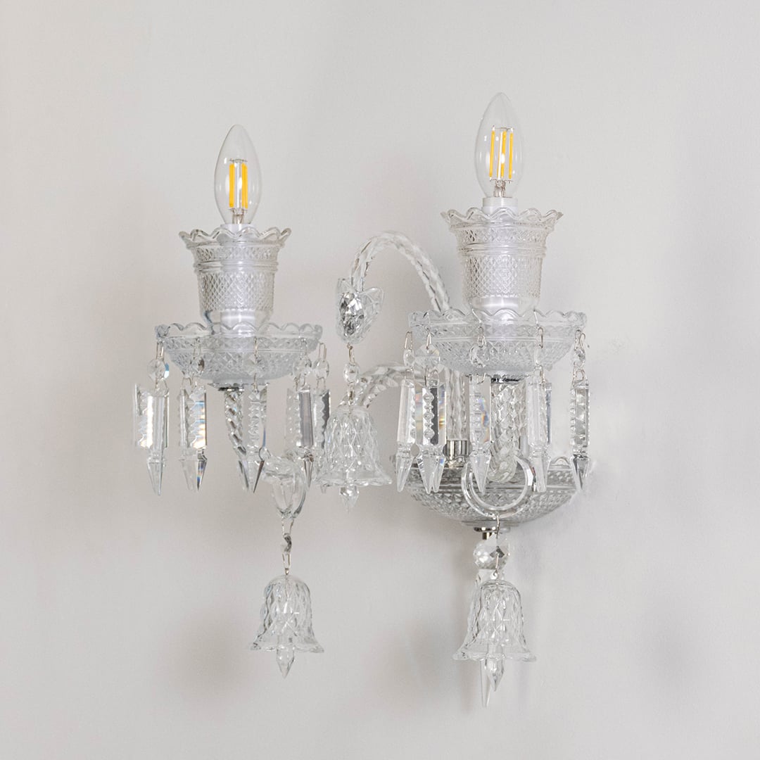 Double arm crystal wall light with detailed glass design and crystal drops turned off on white background.