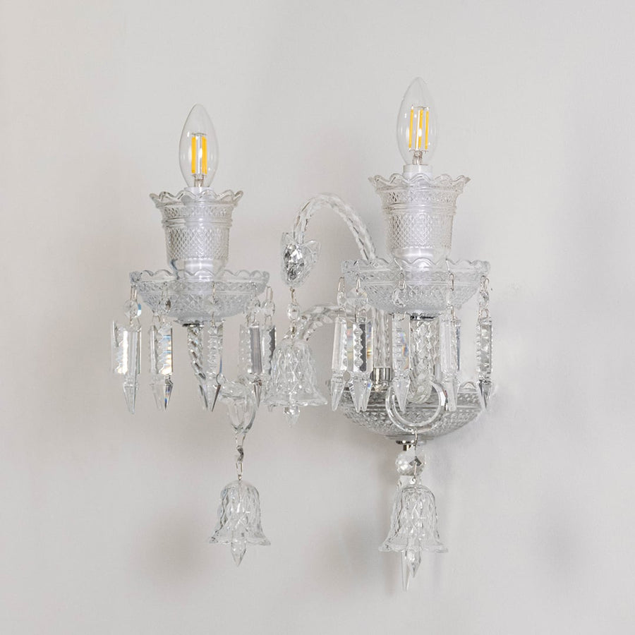 Double arm crystal wall light with detailed glass design and crystal drops turned off on white background.