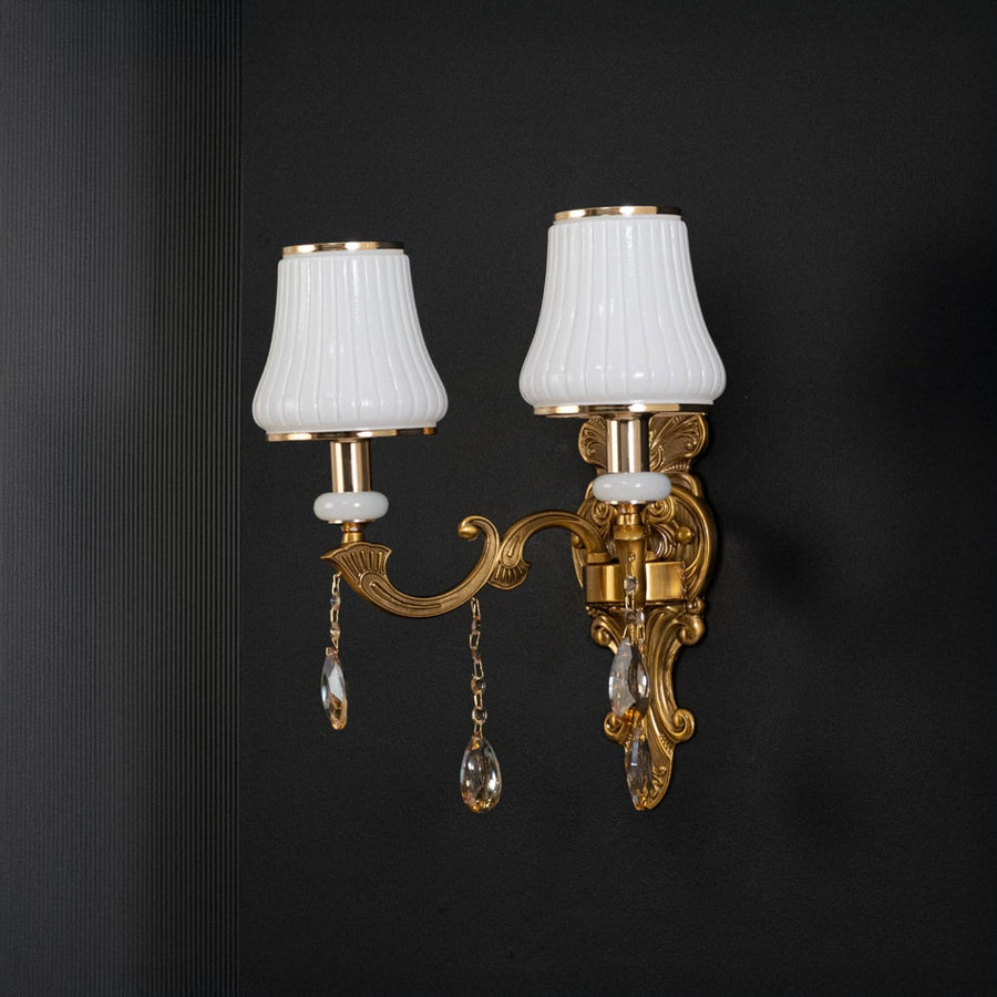 Classic two light crystal sconce with gold base and crystal drops shown switched off on black background.