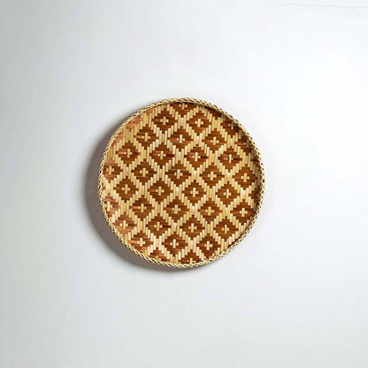Round handcrafted brown and natural seagrass wall basket with geometric pattern on white background image.