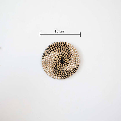 Handwoven seagrass round wall basket decor in natural beige with black spiral woven pattern and size guide on white.