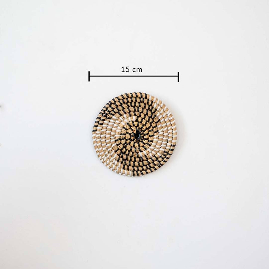 Handwoven seagrass round wall basket decor in natural beige with black spiral woven pattern and size guide on white.