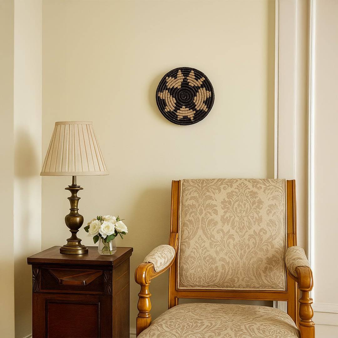 Rustic chair with patterned backrest next to a wooden side table with a lamp and flowers, against a beige wall with a decorative plate.