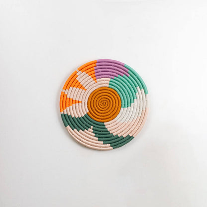 Natural woven multicolor seagrass wall basket with orange green cream and pink pattern on white background image.