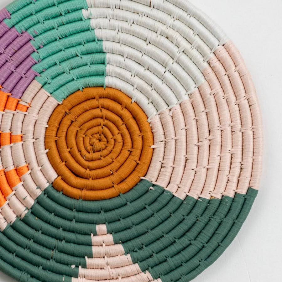 Closeup of handcrafted multicolor seagrass wall basket with orange green cream and white woven pattern for home décor.