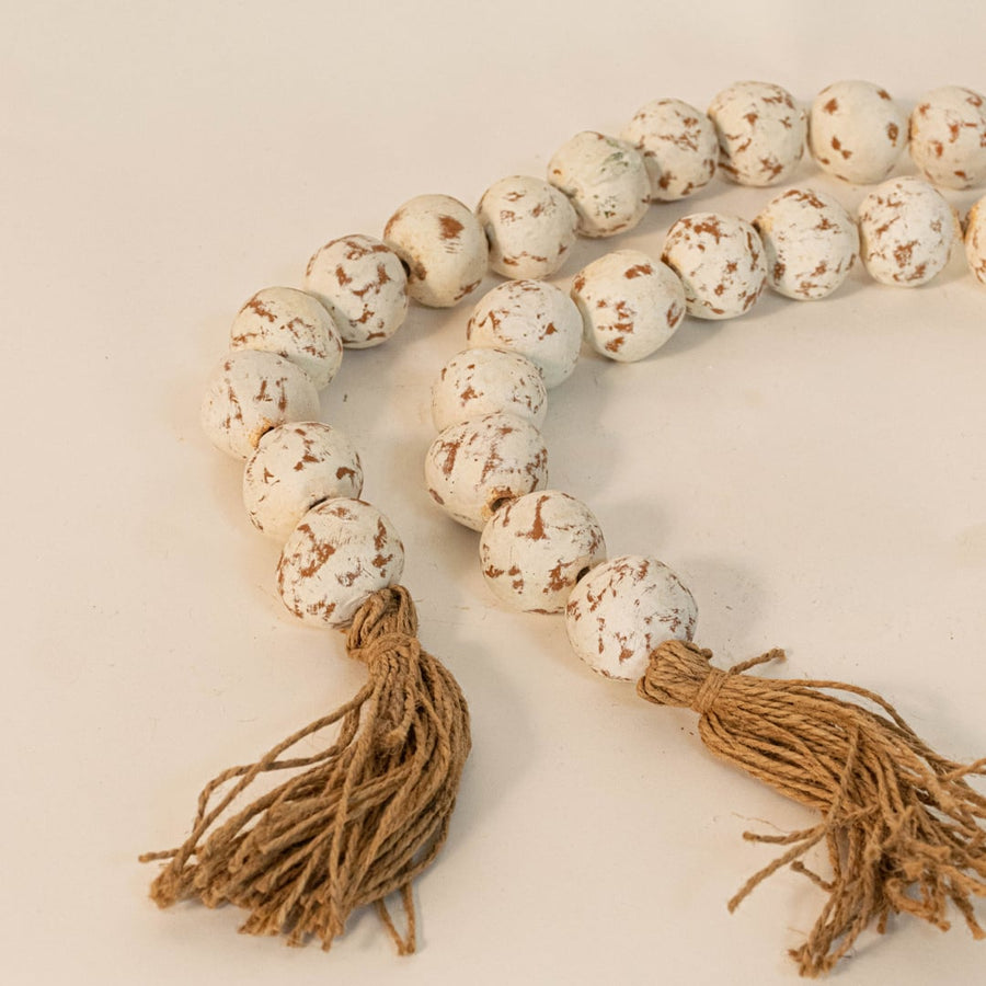 Close-up of speckled bead garland showing unique handcrafted bead detailing and natural jute tassel design.