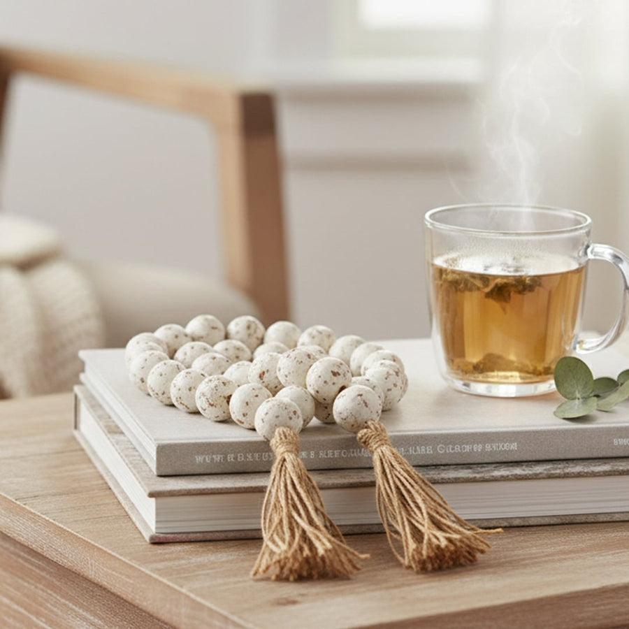 Speckled bead garland placed on stacked books beside a cup of tea creating a soft and cozy home decor vibe.