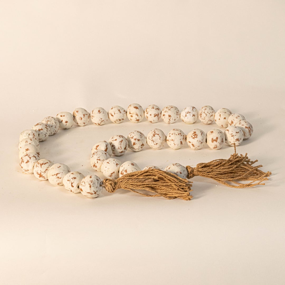 Rustic speckled bead garland captured under warm light on white background showcasing handmade detail.
