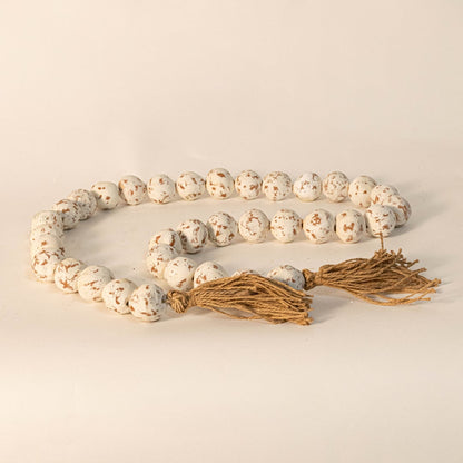 Rustic speckled bead garland captured under warm light on white background showcasing handmade detail.