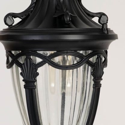 Traditional black metal outdoor lantern closeup showing ornate frame detailing and clear ribbed glass panels for vintage style lighting.