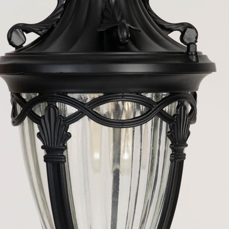 Traditional black metal outdoor lantern closeup showing ornate frame detailing and clear ribbed glass panels for vintage style lighting.