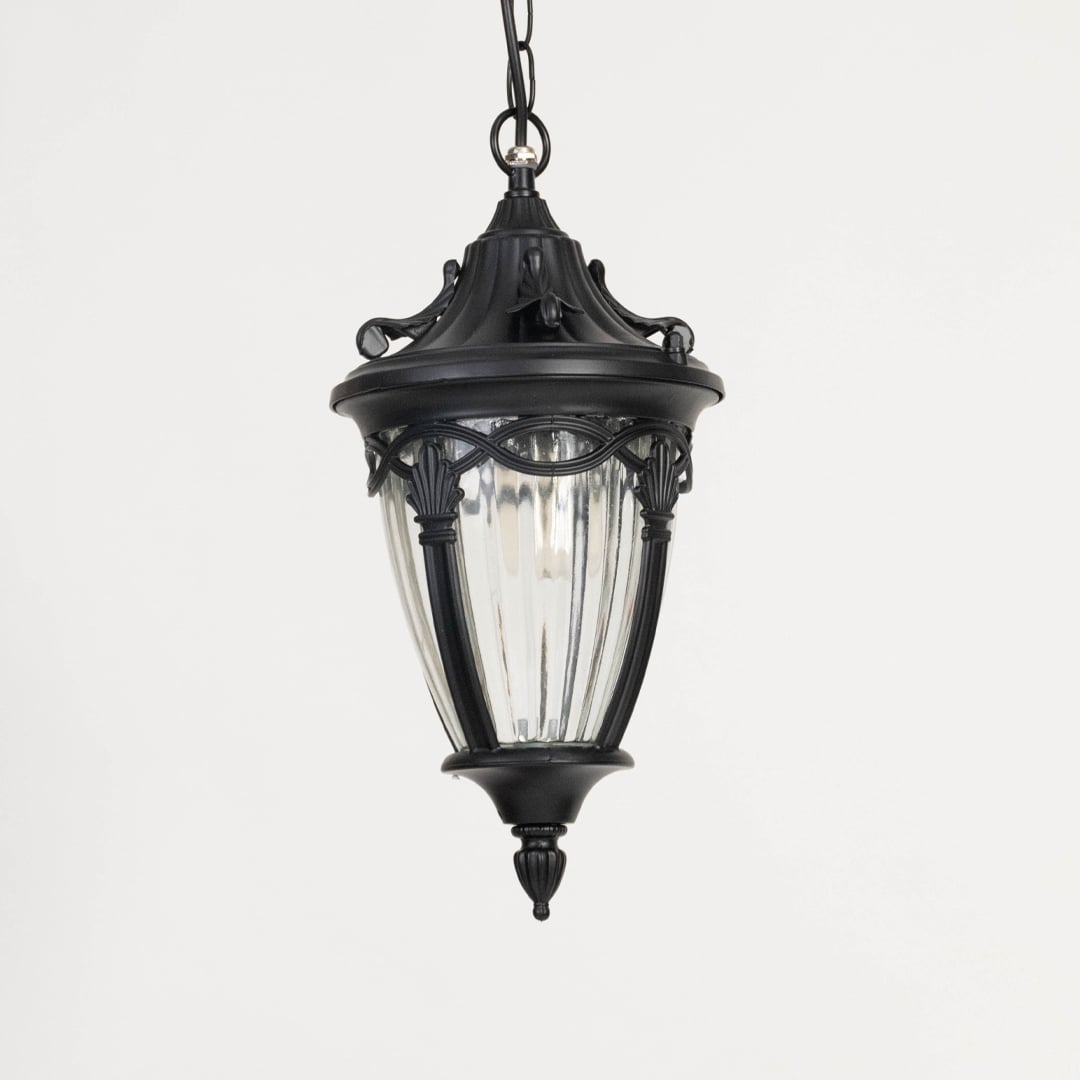 Unlit black metal globe hanging light fixture with decorative circular pattern cage isolated against a plain white background.