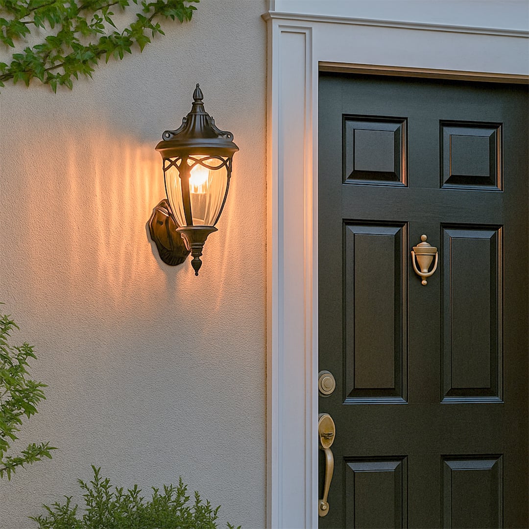Black classic outdoor wall lantern with the light on casting a warm glow beside the entrance door creating an elegant and inviting exterior ambiance for the home.