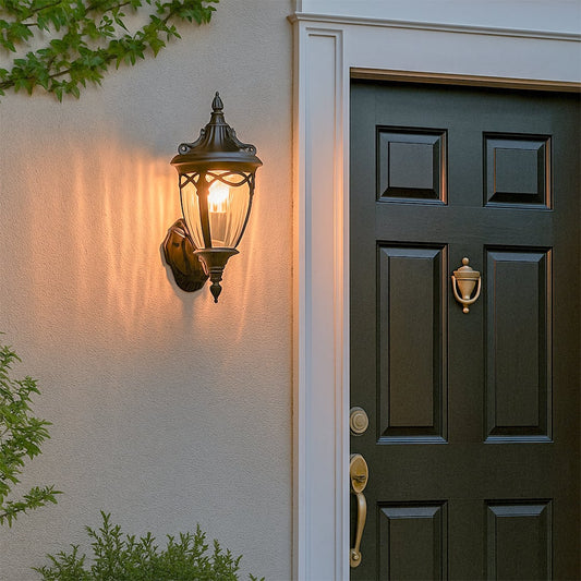 Black classic outdoor wall lantern with the light on casting a warm glow beside the entrance door creating an elegant and inviting exterior ambiance for the home.